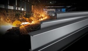Vigas de aço em destaque diante de uma linha industrial com faíscas de corte, representando a expertise da Fultec Inox em fundição de ligas especiais para a indústria.